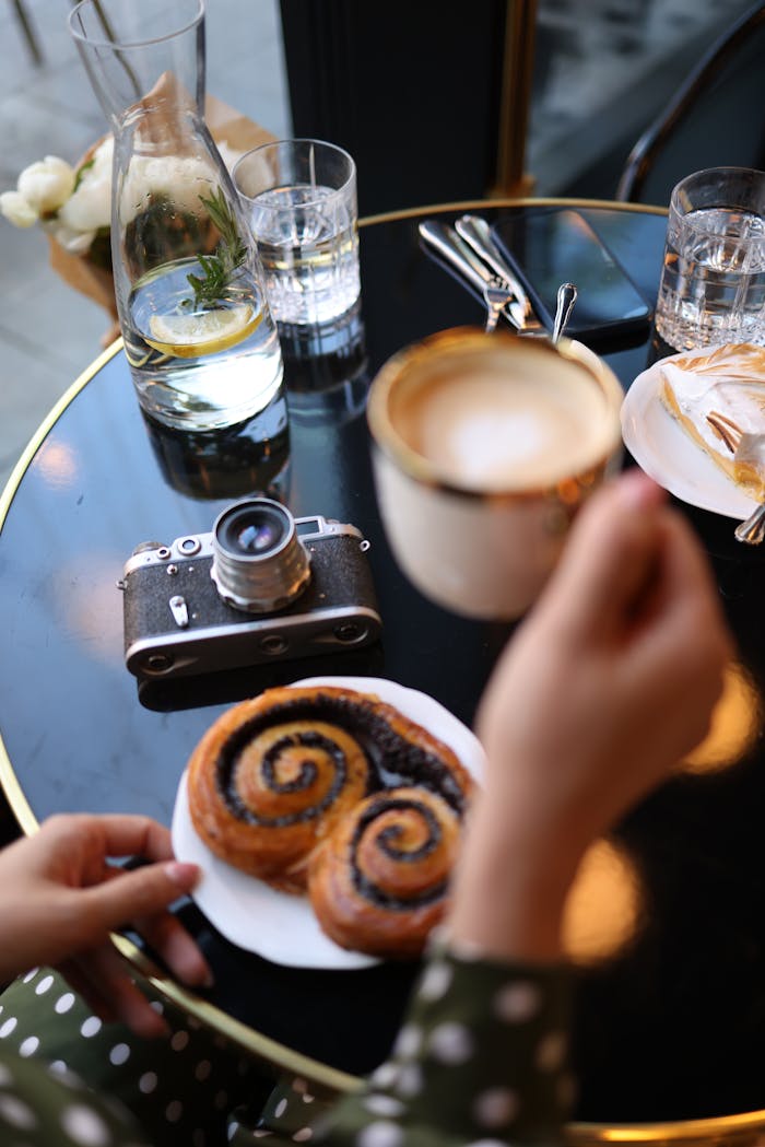 Elegant breakfast scene with retro camera, coffee, and pastry on a stylish table.